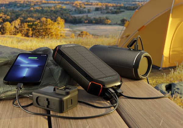 Portable solar power bank charging a phone with a scenic camping background